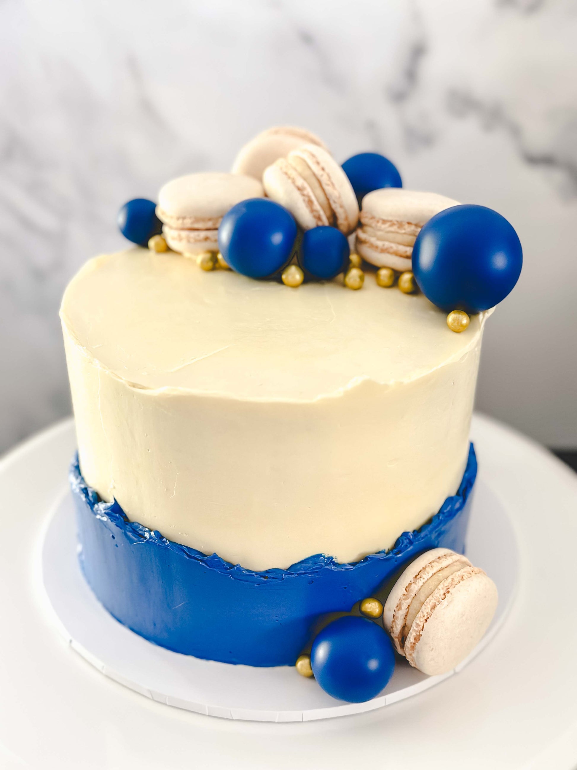 buttercream white and blue cake with blue balls and gold details