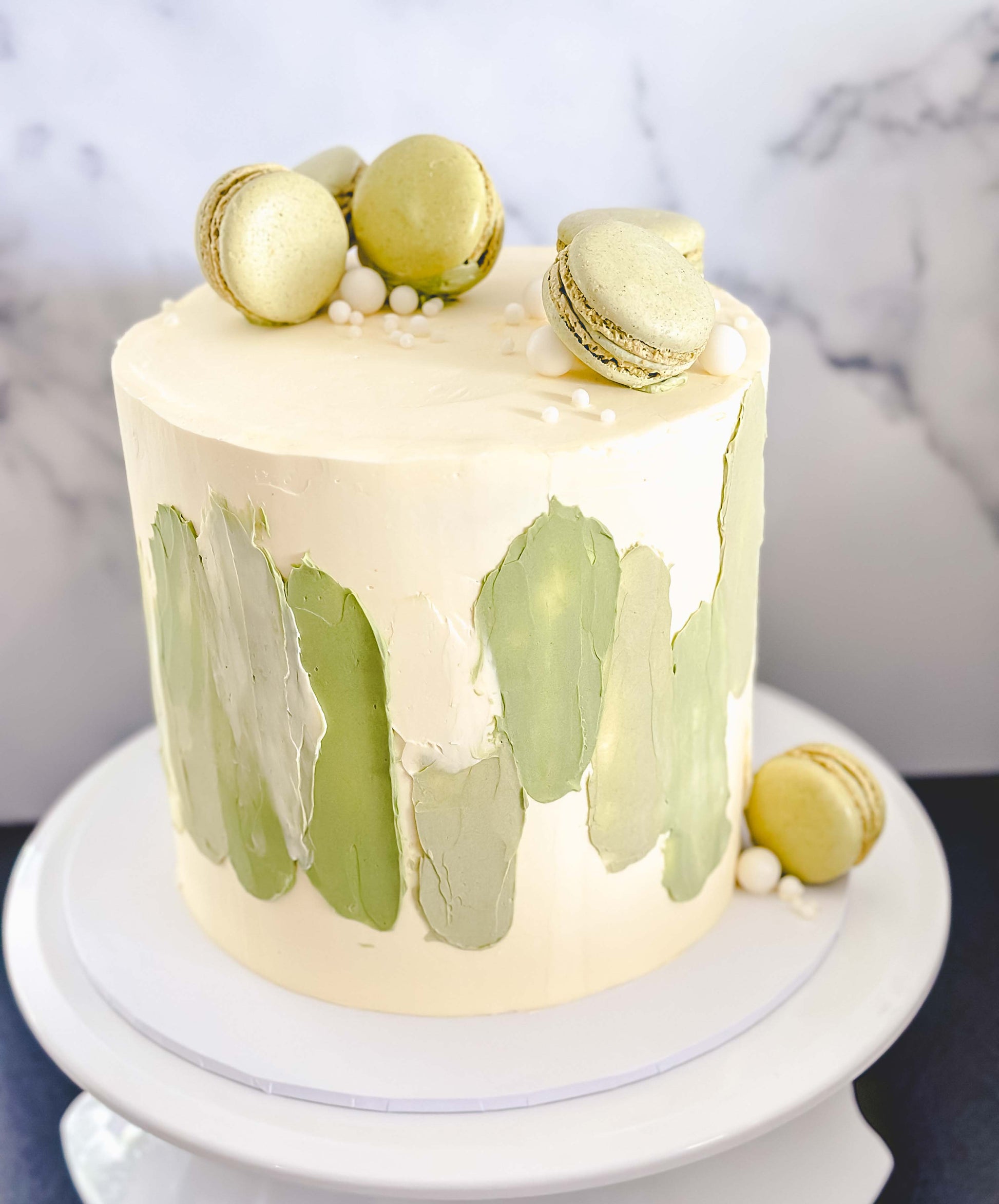 cake with white and green decorative pattern and  green macarons