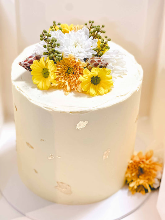 tall vanilla cake with yellow flowers and gold