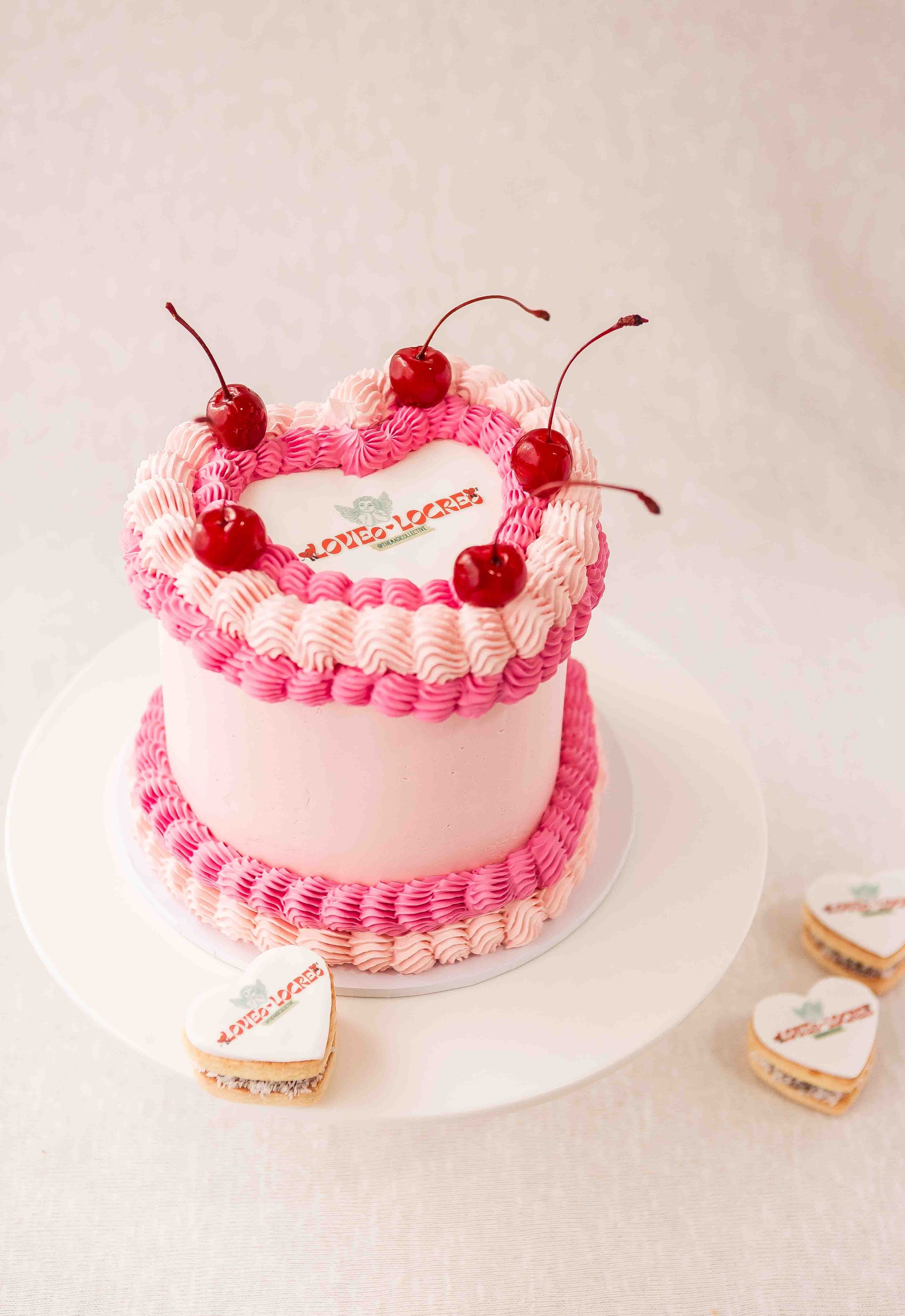 Heart‑shaped pink and fuchsia cake with a personalized logo and personalized heart alfajores, made in Perth.